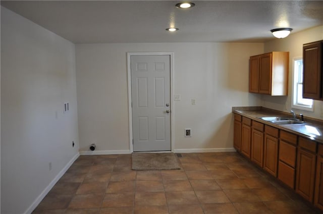 clothes washing area with sink and dark tile patterned floors