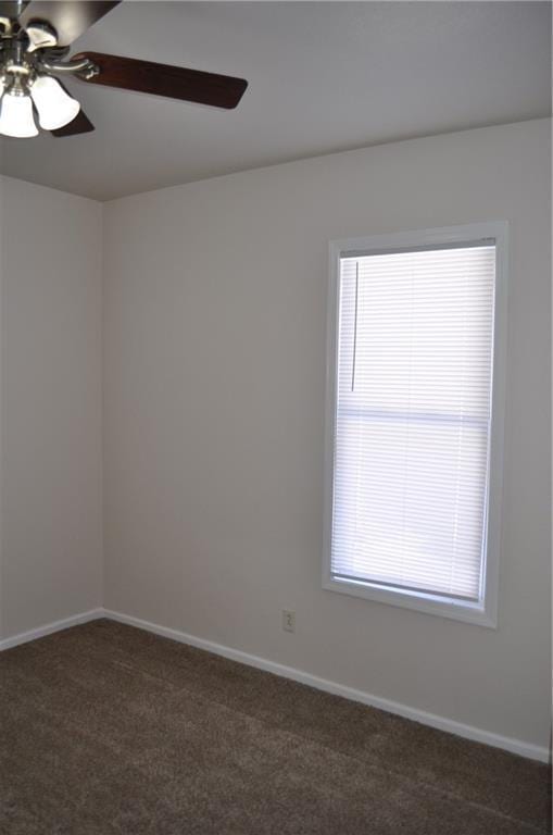 unfurnished room with plenty of natural light, ceiling fan, and dark colored carpet