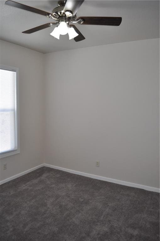 spare room featuring ceiling fan and dark carpet