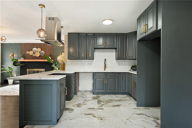 kitchen featuring sink, island range hood, kitchen peninsula, pendant lighting, and backsplash