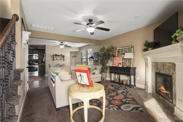 living room featuring a tiled fireplace and ceiling fan