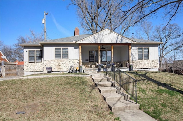 view of front of house featuring a porch, stone siding, a chimney, and a front yard