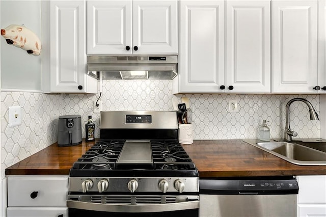 kitchen featuring sink, wooden counters, appliances with stainless steel finishes, white cabinetry, and tasteful backsplash