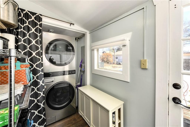 laundry area with stacked washing maching and dryer and dark wood-type flooring