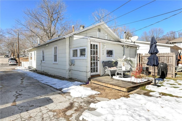 snow covered back of property featuring a wooden deck