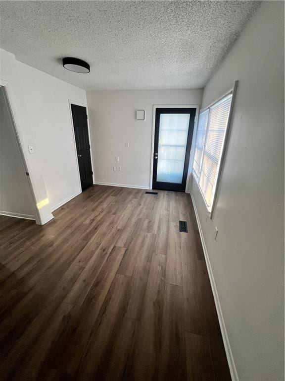 unfurnished room with dark wood-type flooring and a textured ceiling