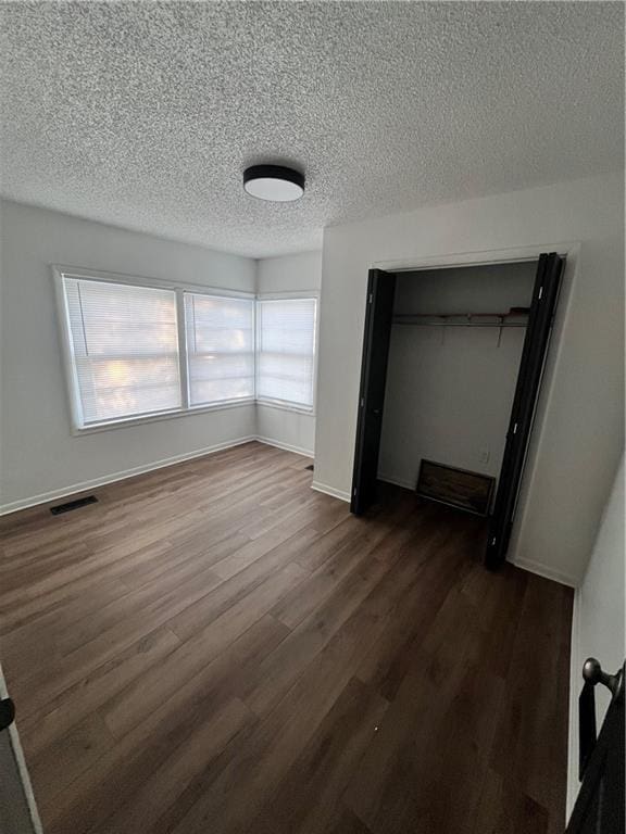 unfurnished bedroom featuring a closet, dark hardwood / wood-style floors, and a textured ceiling