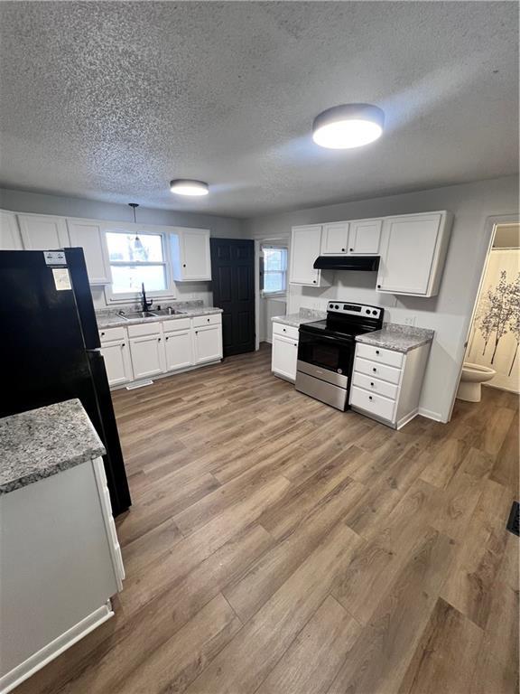 kitchen with sink, white cabinetry, black refrigerator, a textured ceiling, and stainless steel range with electric cooktop