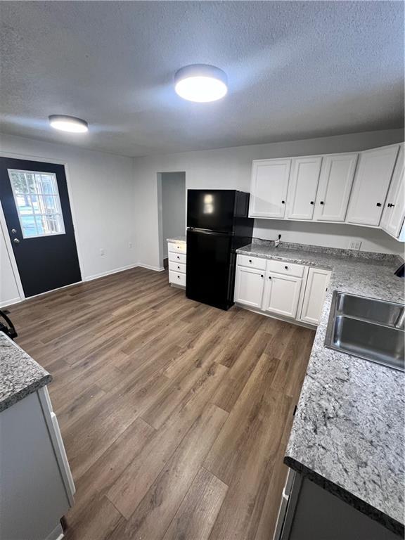 kitchen featuring white cabinetry, black fridge, sink, and a textured ceiling