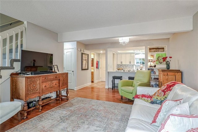 living room featuring a textured ceiling, light hardwood / wood-style flooring, and a chandelier