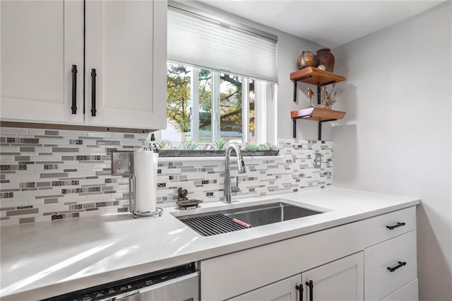 kitchen featuring white cabinetry, sink, stainless steel dishwasher, and backsplash