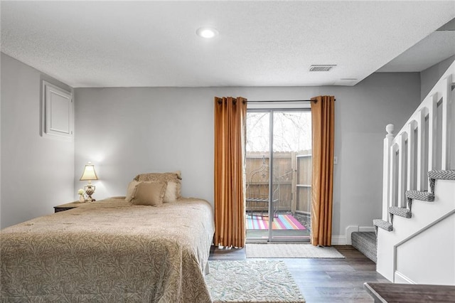 bedroom with access to exterior, hardwood / wood-style floors, and a textured ceiling