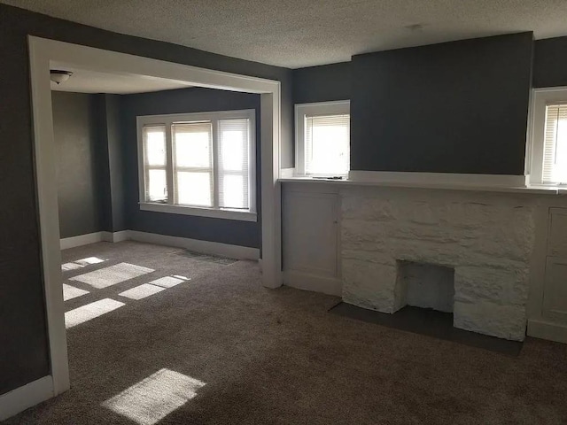 unfurnished living room featuring a fireplace, carpet floors, and a textured ceiling