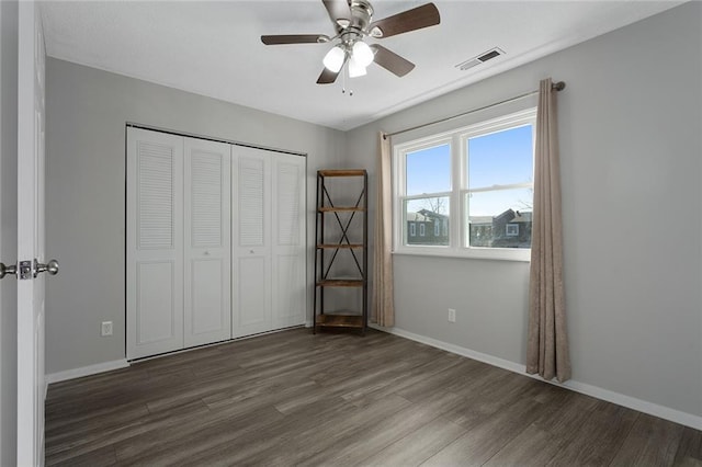 unfurnished bedroom with dark wood-type flooring, a closet, and ceiling fan