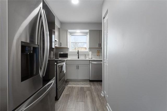 kitchen with gray cabinetry, sink, wood-type flooring, and appliances with stainless steel finishes