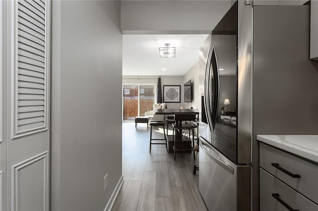 kitchen with light stone counters, stainless steel refrigerator, and light wood-type flooring