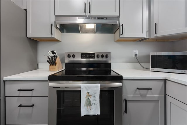 kitchen with light stone countertops, white cabinetry, and appliances with stainless steel finishes