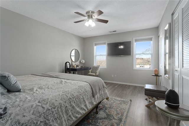 bedroom with hardwood / wood-style flooring, ceiling fan, and a textured ceiling