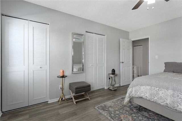 bedroom with ceiling fan, dark hardwood / wood-style flooring, and two closets