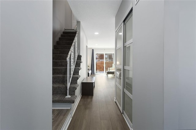 corridor with baseboards, stairway, dark wood-style flooring, a textured ceiling, and recessed lighting