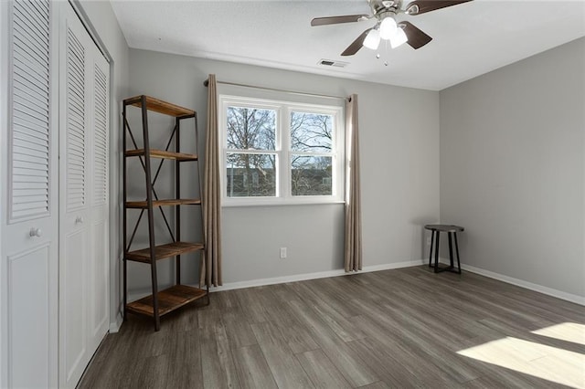 unfurnished bedroom with a closet, visible vents, ceiling fan, wood finished floors, and baseboards