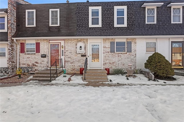 townhome / multi-family property featuring brick siding and roof with shingles