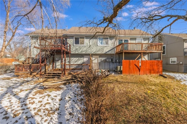 snow covered house with a wooden deck and central AC unit