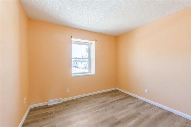 spare room with light hardwood / wood-style floors and a textured ceiling