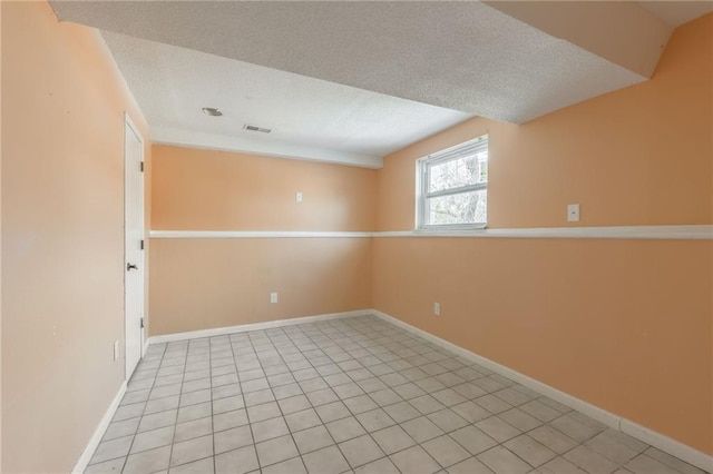 tiled empty room featuring a textured ceiling