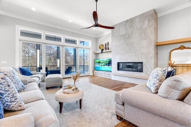 living room with a tiled fireplace, crown molding, and wood-type flooring