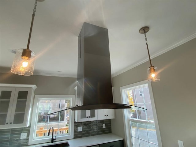 kitchen with tasteful backsplash, crown molding, island exhaust hood, and white cabinets