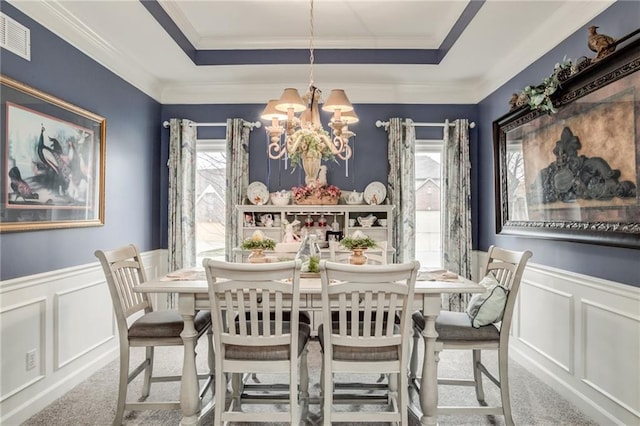 dining room featuring a raised ceiling, carpet, and wainscoting