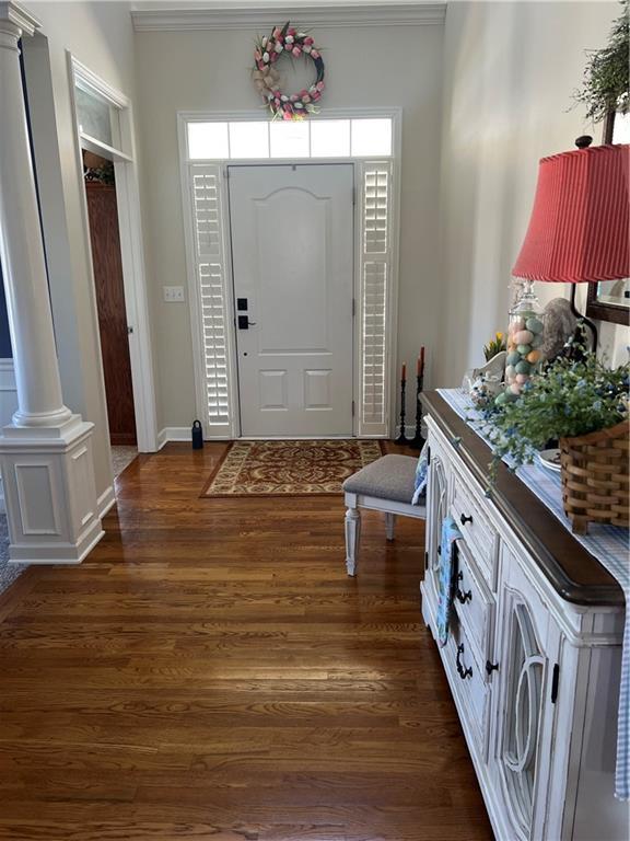 entryway with baseboards, dark wood-type flooring, and ornate columns