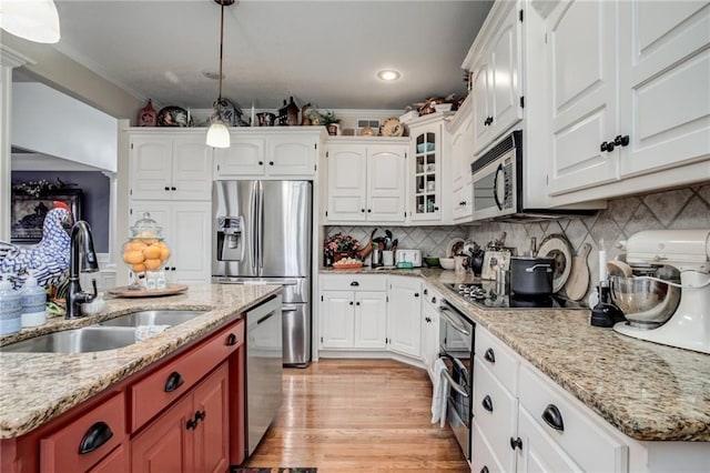 kitchen featuring a sink, stainless steel appliances, crown molding, light wood finished floors, and decorative backsplash