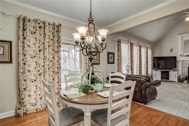 dining area featuring a fireplace, crown molding, an inviting chandelier, and wood finished floors