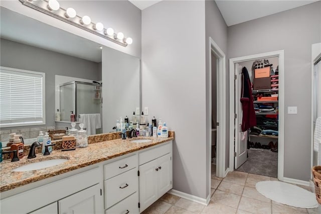 bathroom featuring a sink, double vanity, a shower stall, and tile patterned floors