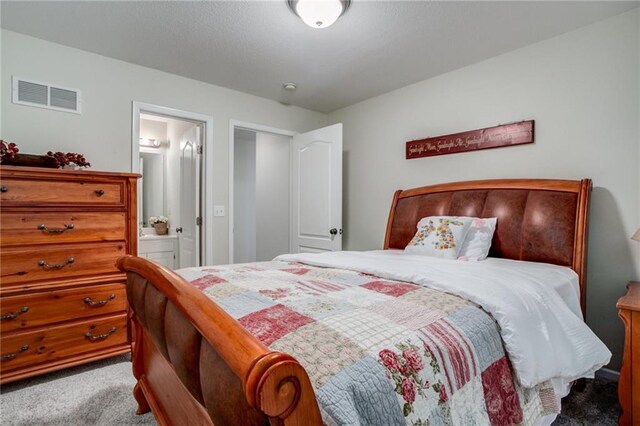 carpeted bedroom with visible vents and ensuite bath