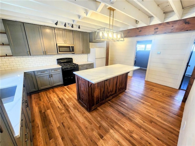 kitchen featuring dark wood-type flooring, hanging light fixtures, white refrigerator, light stone countertops, and black gas range