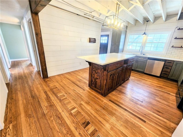 kitchen with a kitchen island, pendant lighting, tasteful backsplash, stainless steel dishwasher, and light wood-type flooring