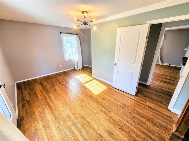 unfurnished bedroom featuring hardwood / wood-style floors and a notable chandelier