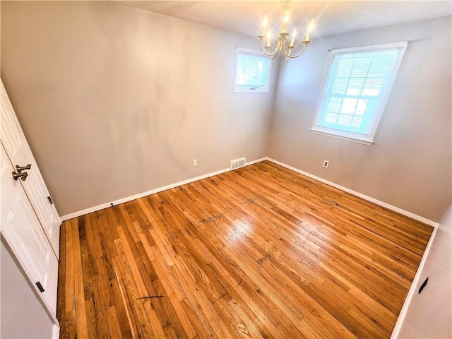 empty room with a notable chandelier and light wood-type flooring