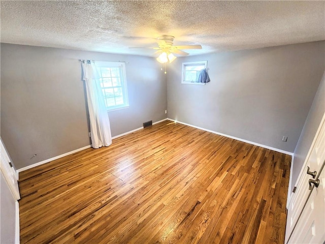 unfurnished room featuring ceiling fan, plenty of natural light, light hardwood / wood-style floors, and a textured ceiling