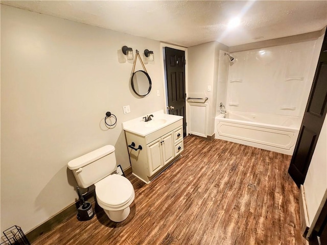 full bathroom with vanity, wood-type flooring, a textured ceiling, shower / washtub combination, and toilet