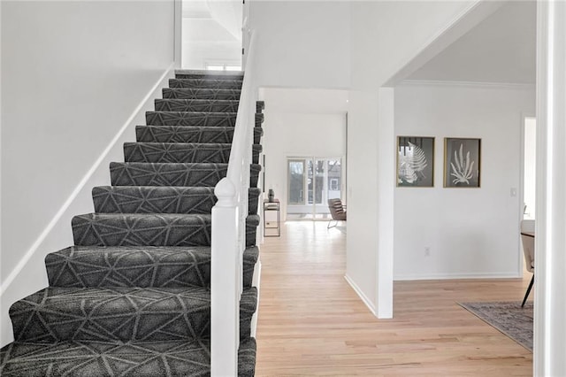 stairs with ornamental molding and wood-type flooring