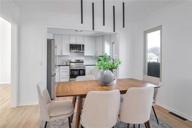 dining room featuring ornamental molding and light hardwood / wood-style flooring