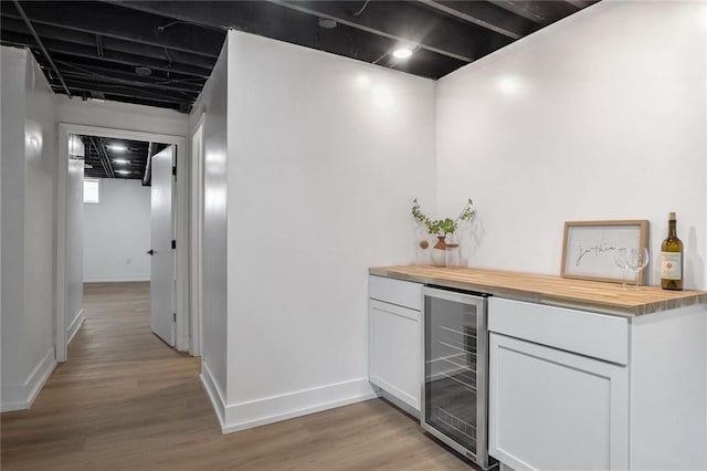 bar with white cabinetry, wine cooler, wooden counters, and light hardwood / wood-style floors