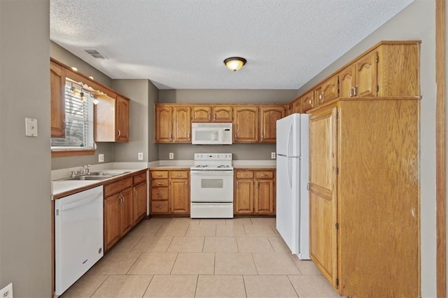 kitchen with white appliances, sink, a textured ceiling, and light tile patterned floors