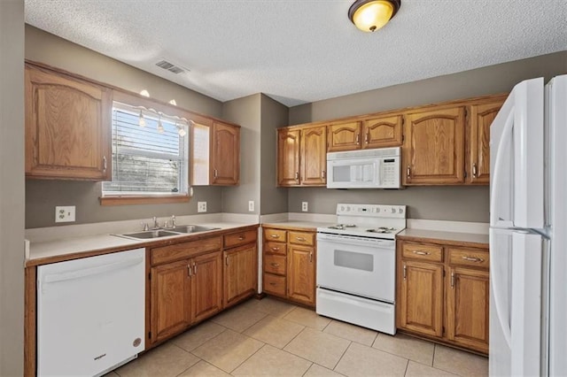 kitchen with sink, white appliances, light tile patterned floors, and a textured ceiling