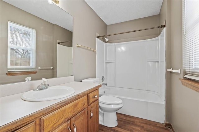 full bathroom with washtub / shower combination, toilet, a textured ceiling, vanity, and hardwood / wood-style floors