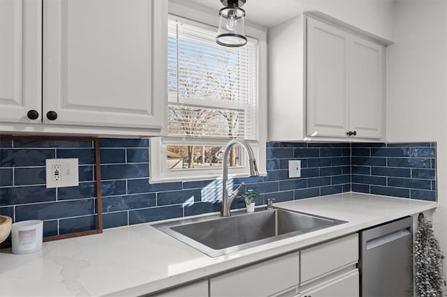 kitchen featuring sink, dishwasher, white cabinetry, light stone counters, and decorative backsplash